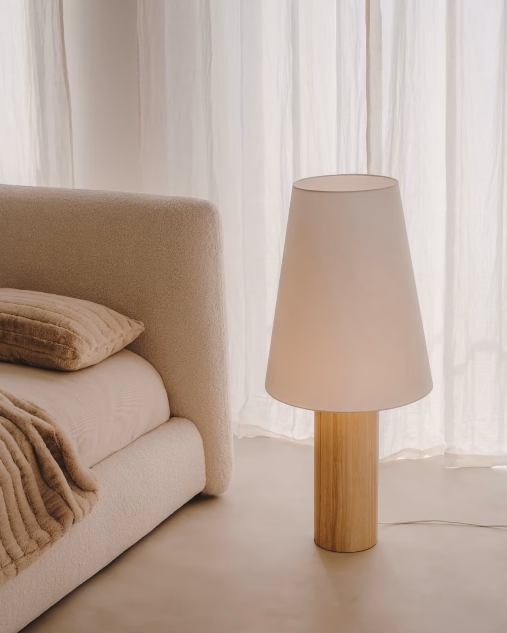 Sculptural floor lamp with natural lamp shade and wood base.